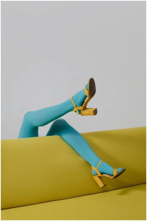 Stylish legs in blue tights and yellow heels on a