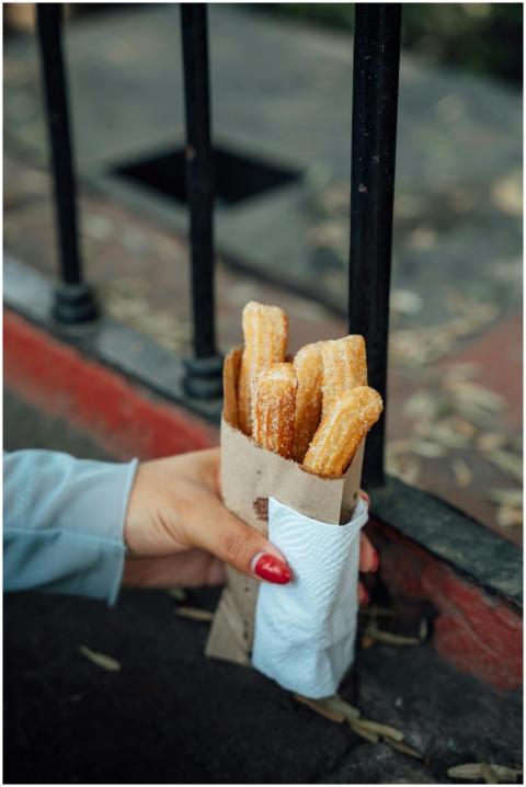 A hand holding sugar-coated churros wrapped in pap