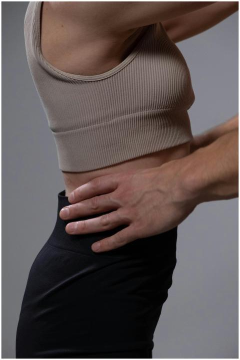 A woman stretches her side in a studio, highlighti