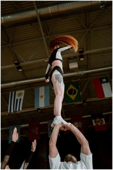Cheerleader upheld by team executing a stunt indoo