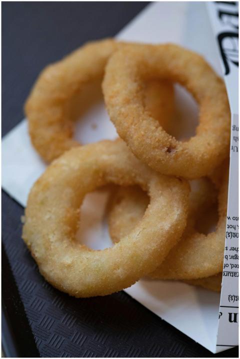 Golden brown onion rings on paper, highlighting th