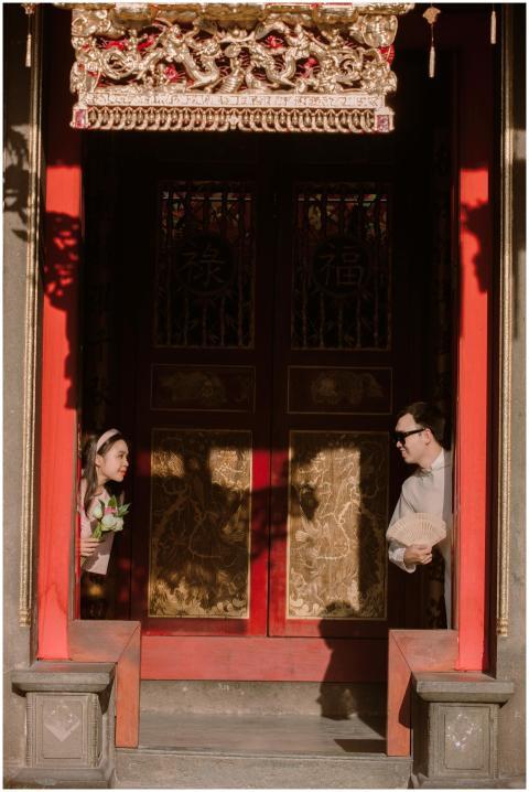 A couple playfully peeks from a traditional Chines