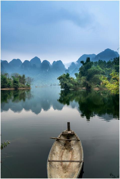 A tranquil river scene with a canoe, misty mountai