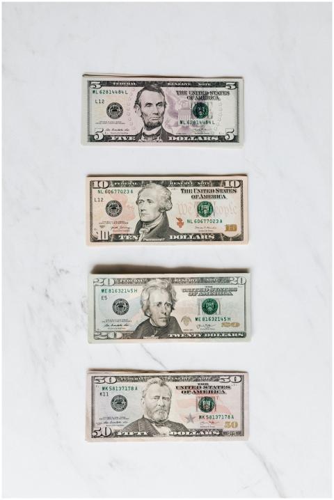 A neat flat lay of US dollar bills on a white marb