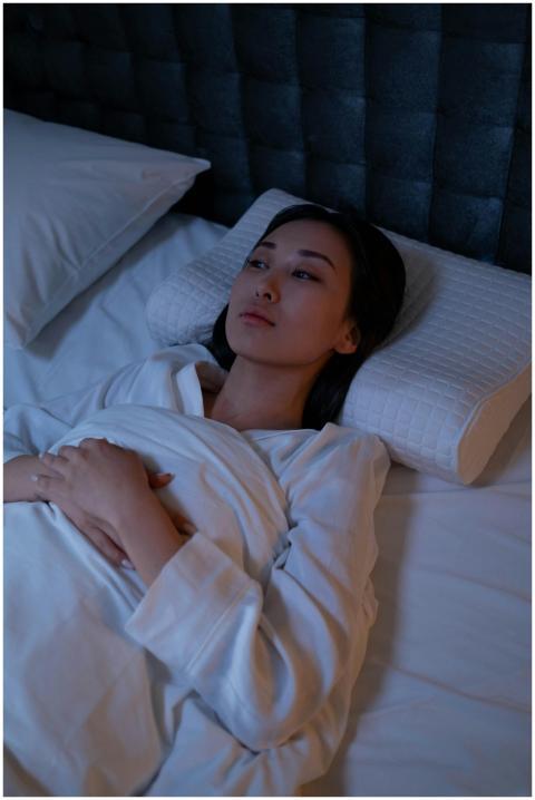 An Asian woman lying awake in bed, reflecting on h