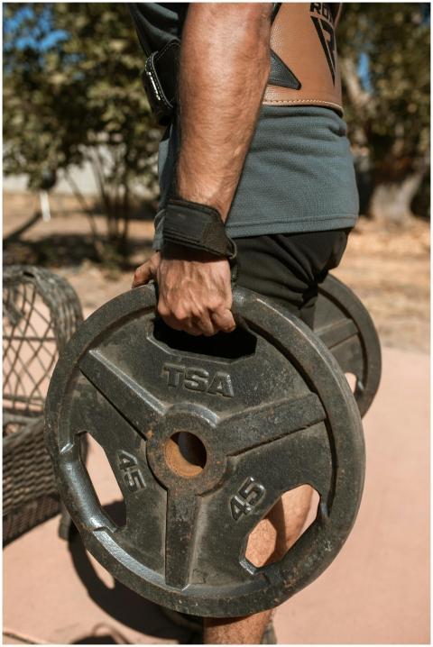 Athletic man lifting gym weights outdoors, showcas