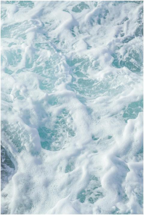 A close-up of swirling sea foam and turquoise wave