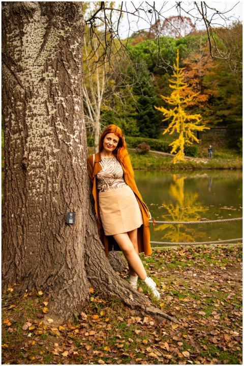Woman leaning against tree with autumn colors in İ