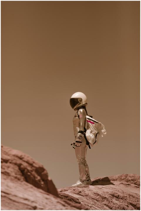 Astronaut in spacesuit standing on rocky terrain w