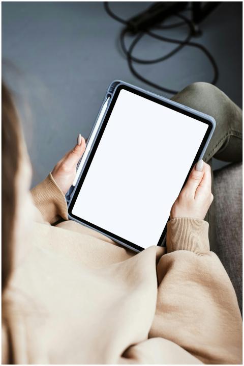 A person holding a tablet with a blank screen, ide
