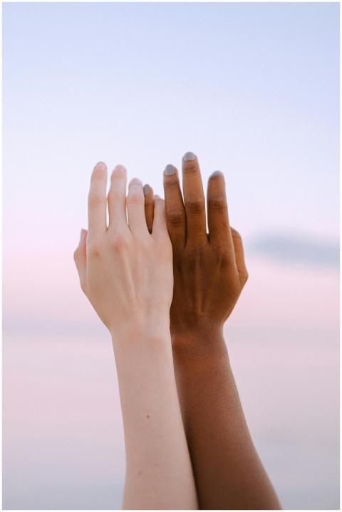 Two hands of different ethnicities reaching toward