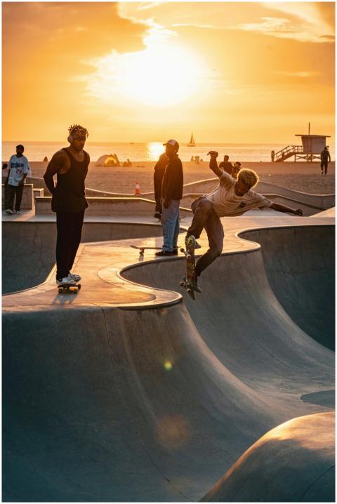 Dynamic skateboarders perform tricks at beach skat