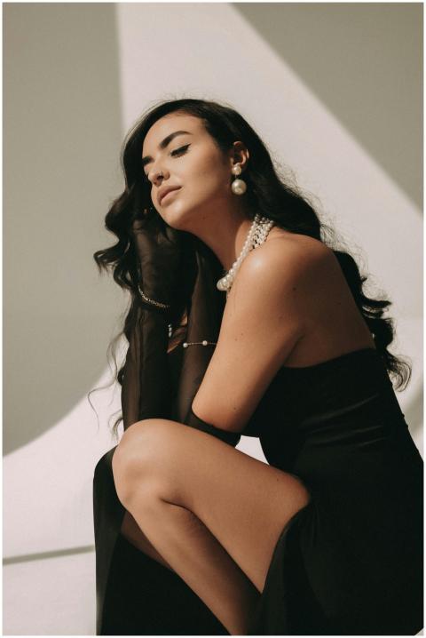 Woman in elegant black dress with pearl jewelry, p