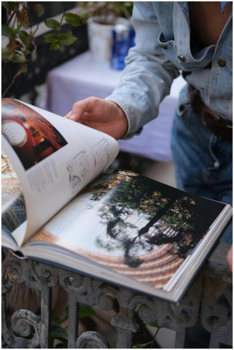 Person in denim browsing a photography book outdoo