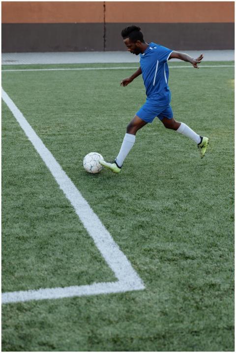 A young male soccer player kicks the ball on a gre