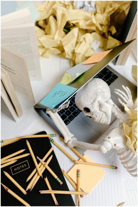 Skeleton at a desk overwhelmed with work symbolizi