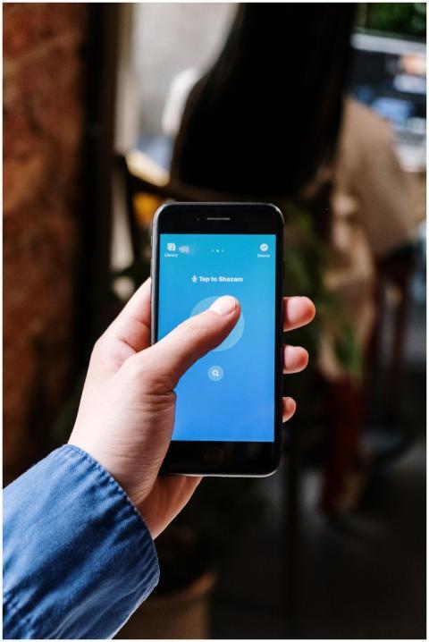 Person uses Shazam app on smartphone, capturing mu