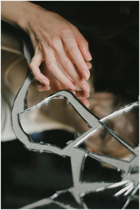 A woman's hands touching a broken mirror, creating