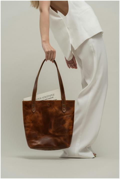 Stylish woman holding a brown leather bag in a min