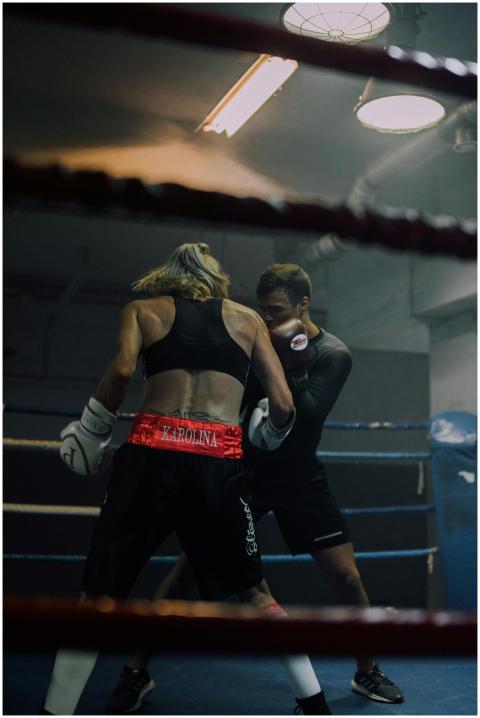 Two athletes sparring in a gym boxing ring, showca
