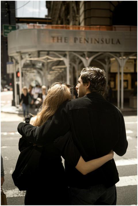 A couple embraces lovingly at a crosswalk near The