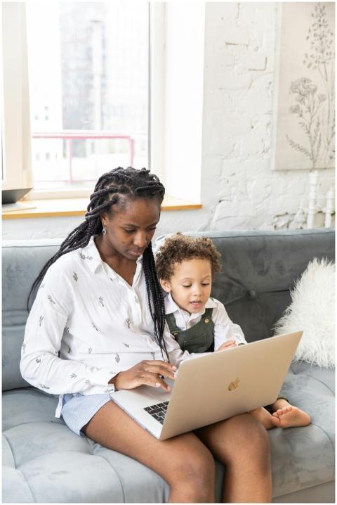 A mother and child sit together using a laptop ind