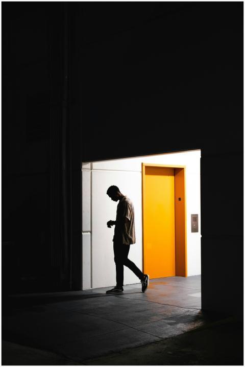 A man walking past a bright yellow elevator door i