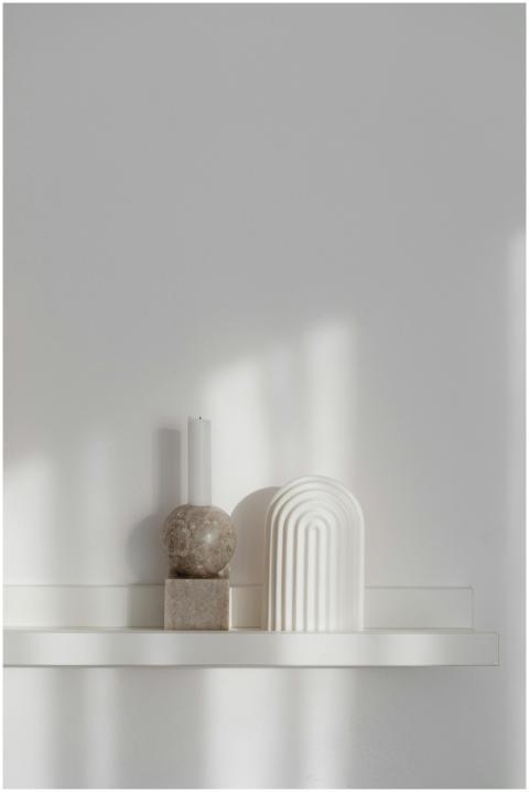 A minimalist shelf featuring a candle holder and m