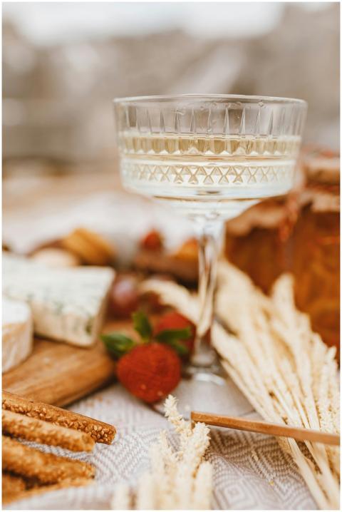 A rustic outdoor picnic scene with cheese, champag