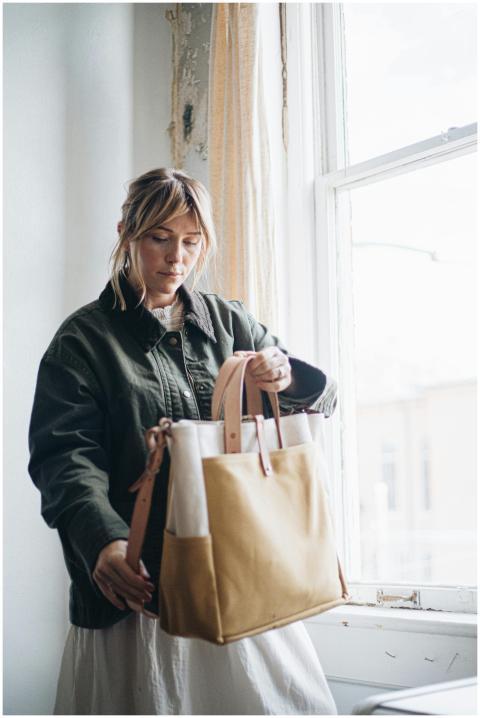 Woman holding a handcrafted canvas tote bag by a w