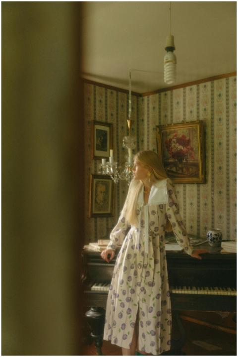 Blonde woman in retro dress leans on piano in a vi