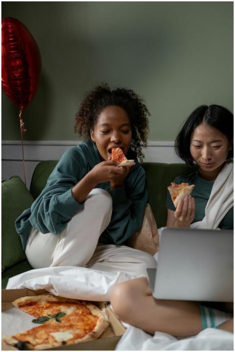 Two friends enjoying pizza and watching a movie to