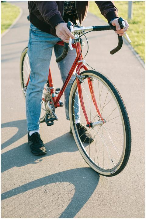 Person in jeans riding a red vintage bicycle on a