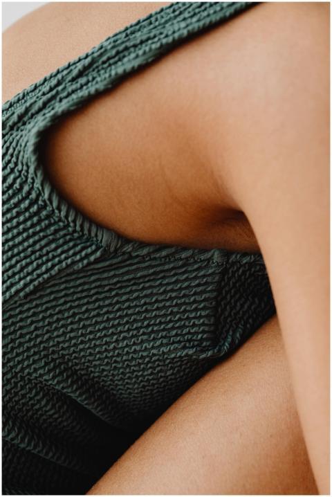 Artistic close-up of green knit cami top against b