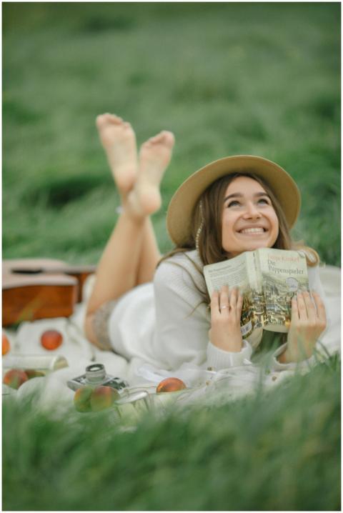 Joyful woman reading a book in a grassy field, sur