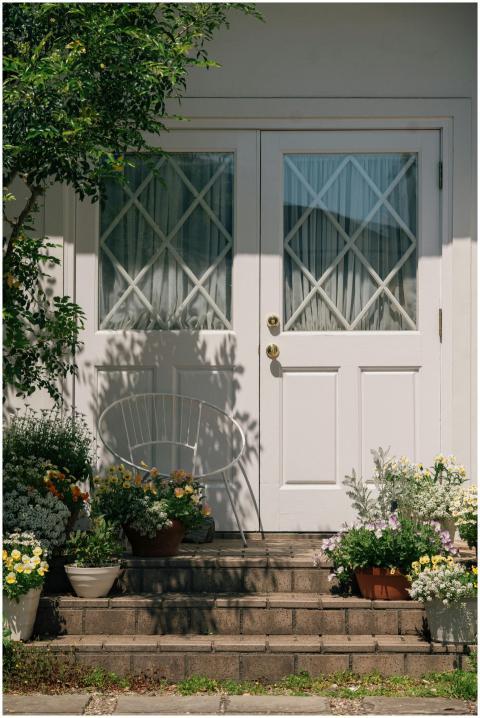 White door entrance surrounded by colorful potted
