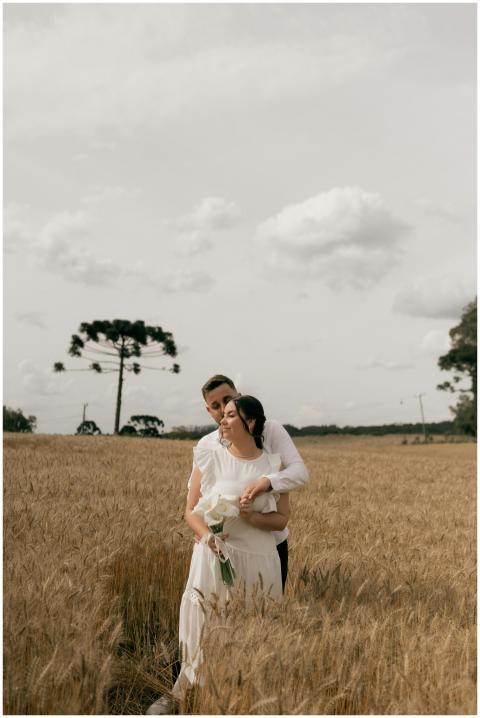 A romantic couple embracing in a tranquil wheat fi