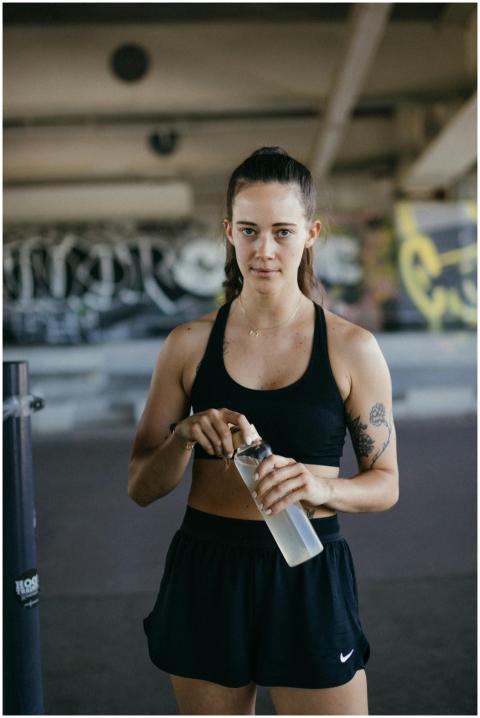Woman in sports bra and shorts holding a water bot