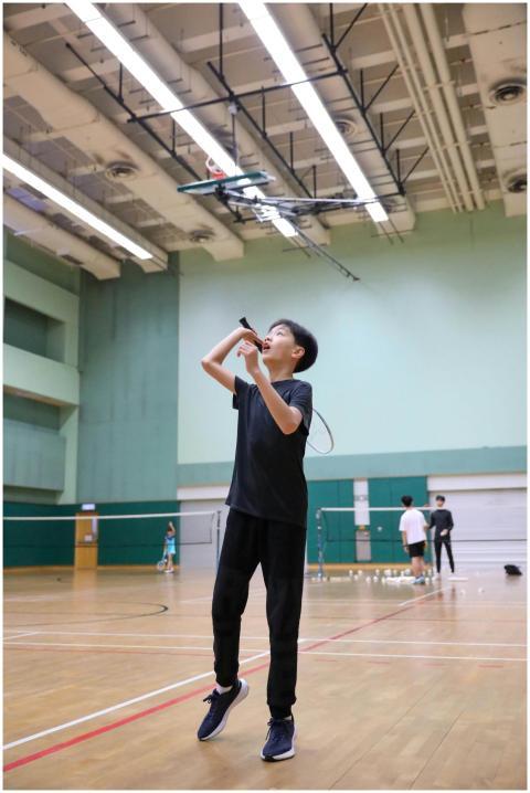 A boy in motion playing badminton indoors, showcas