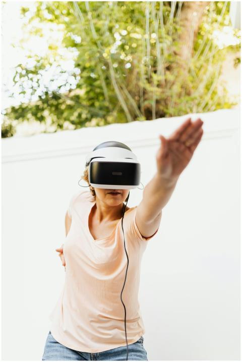 A woman using a VR headset outdoors, reaching upwa