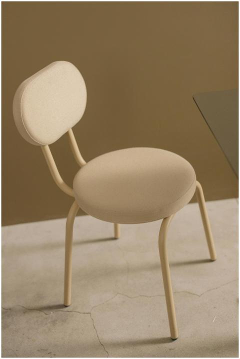 A simple beige chair in a minimalistic setting wit