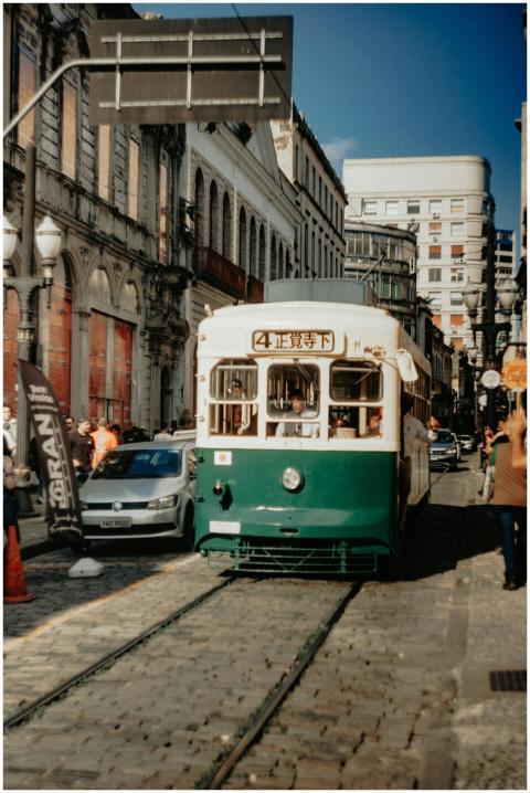 A classic green and white tram travels through a b