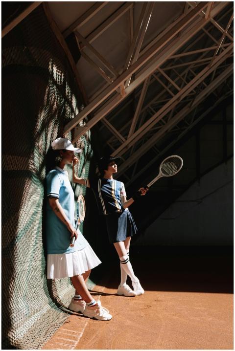 Two young women in trendy tennis outfits posing on