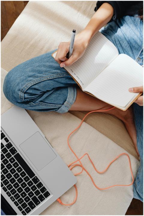 A person in casual attire writing in a notebook be