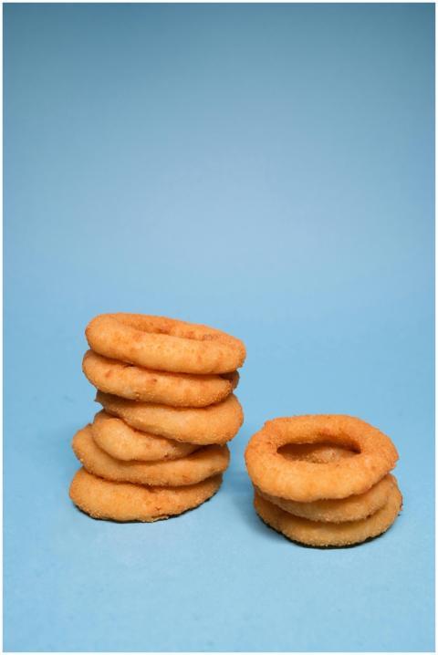 Golden deep fried onion rings on each other on blu