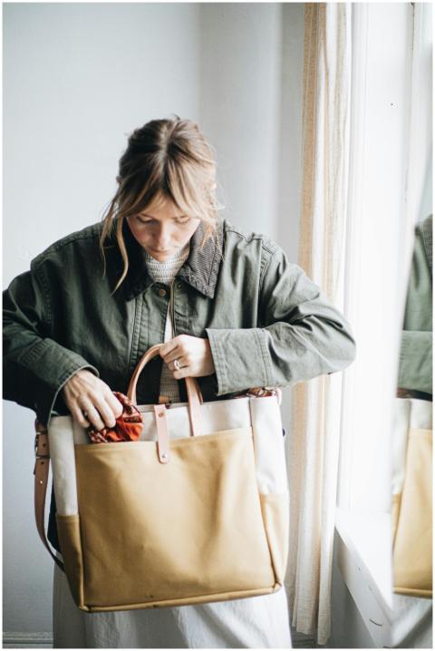 Woman holding a canvas and leather tote bag, showc