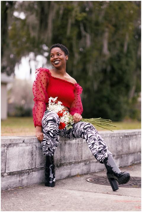 A smiling woman in a red top with flowers, sitting