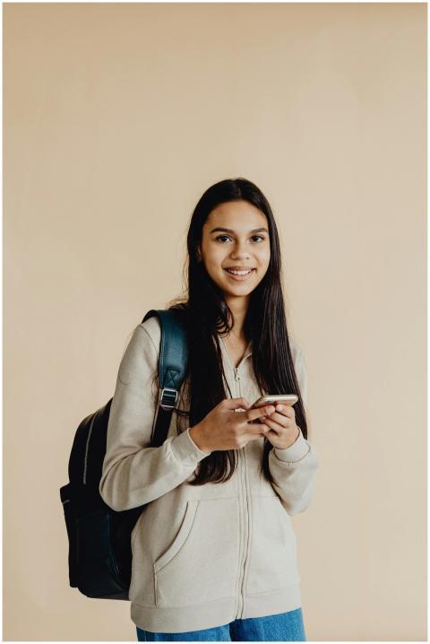 Teenage girl smiling while using smartphone, weari