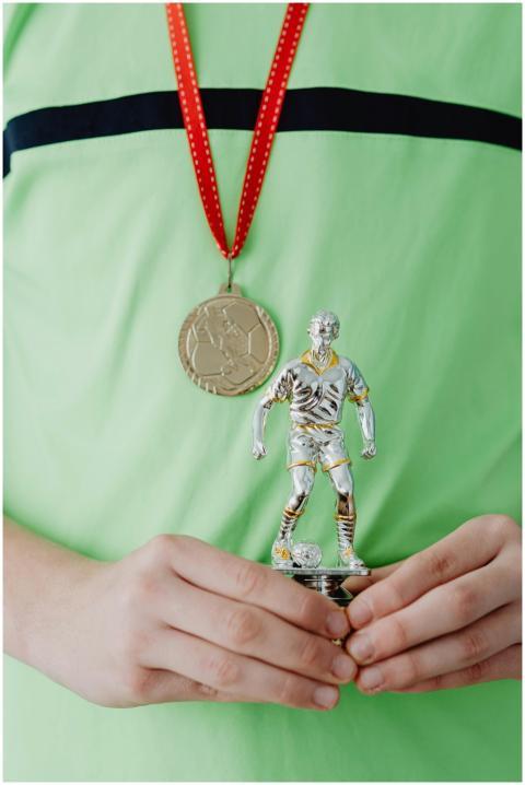 Close-up of hands holding a soccer trophy with a g
