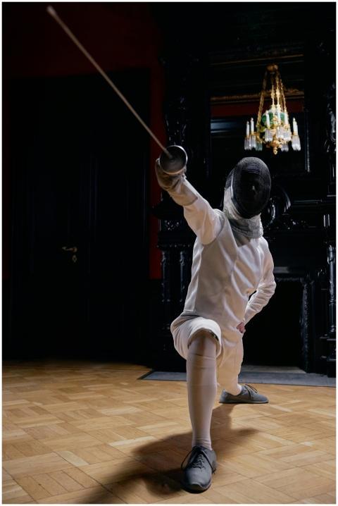 A fencer in full gear striking a dynamic pose with